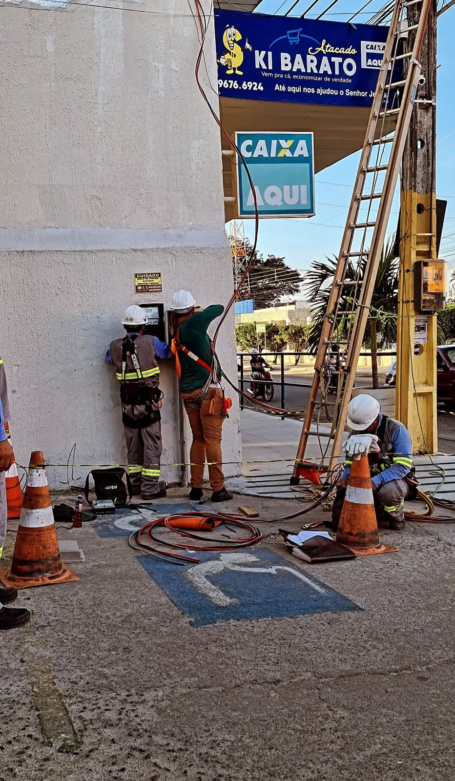 Equipe da D'Luz com capacetes e cintos de segurança instalando o padrão de entrada de um comércio