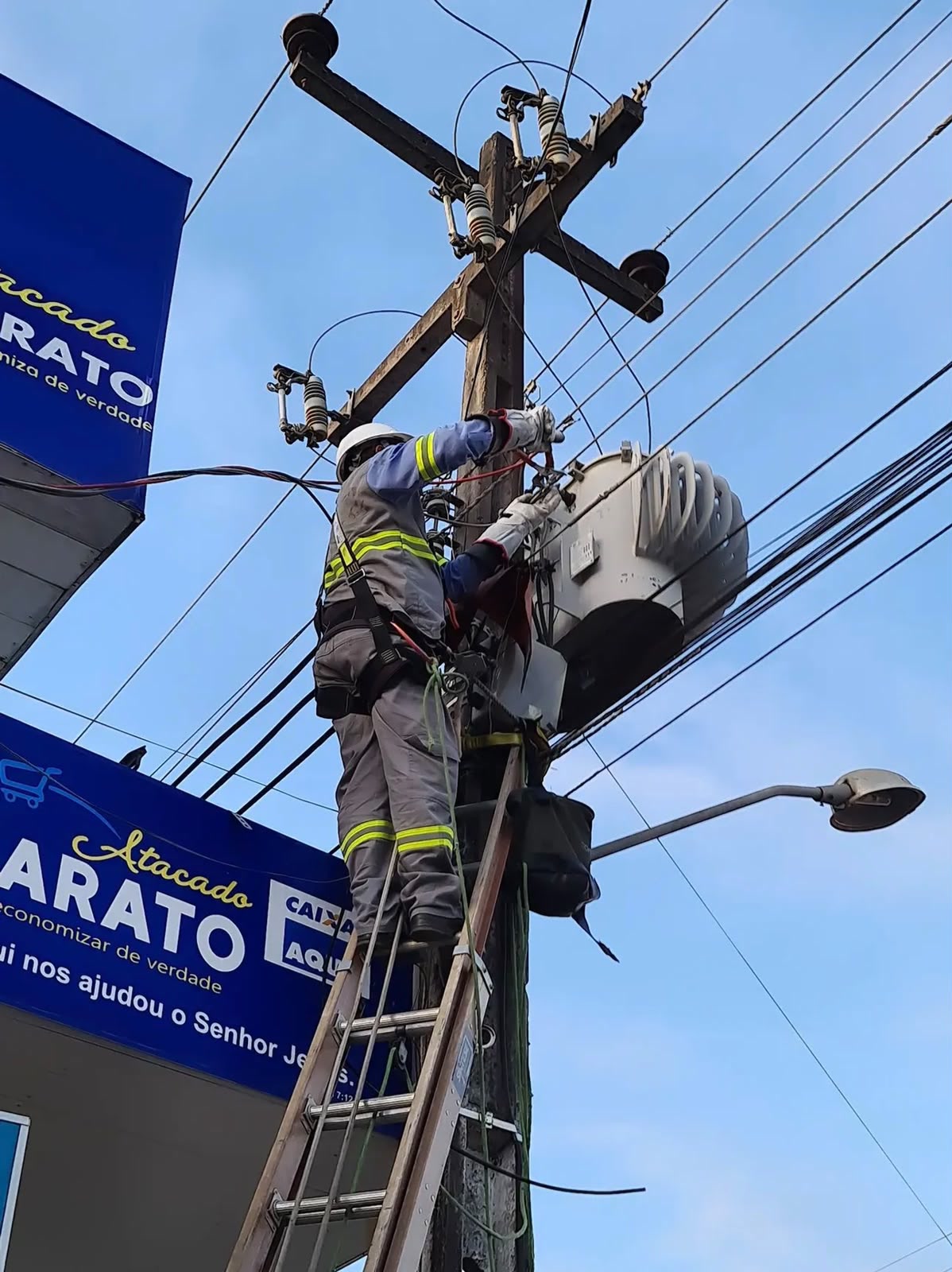 Eletricista da D'Luz com equipamento de segurança trabalhando no alto de um poste