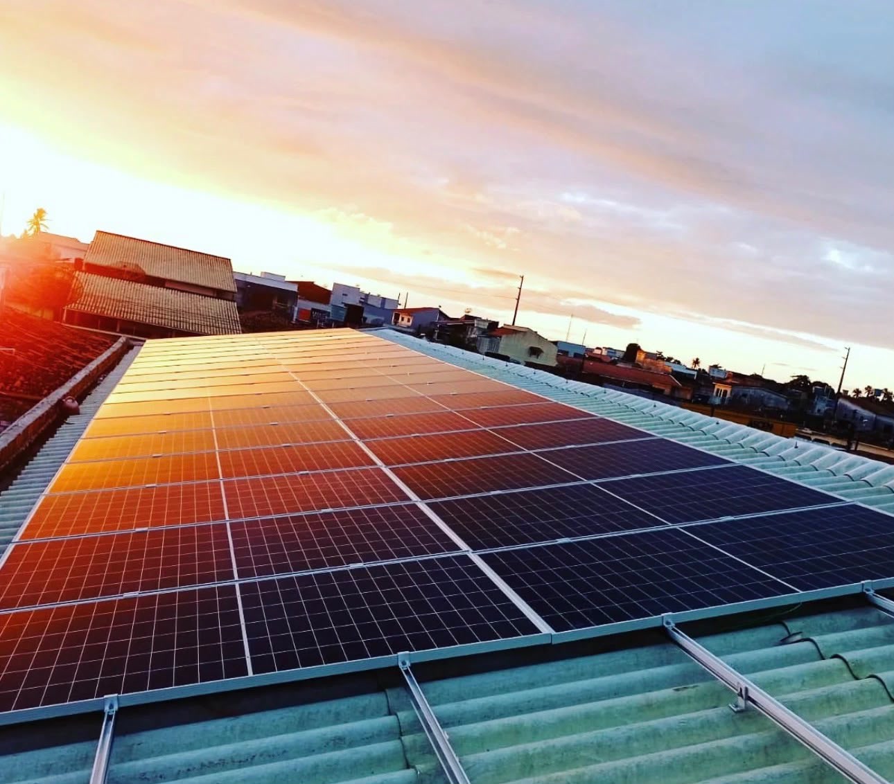 Painéis solares refletindo o pôr do sol num telhado
